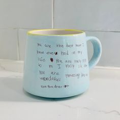 a blue and yellow coffee mug with writing on the inside is sitting on a counter