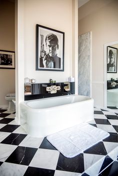 a black and white checkered floor bathroom with a large bathtub in the center