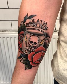 a person with a tattoo on their arm holding a coffee cup and roses in front of them