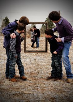 three young men standing in front of a mirror with their hands on each other's shoulders