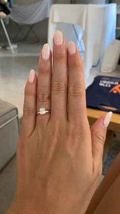 a woman's hand with a white manicure and a diamond ring on it