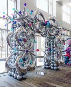 some very pretty balloons in the shape of snowflakes on a wooden floor with large windows