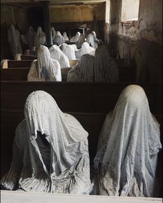 several statues covered in white cloths sitting on pews