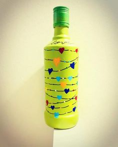 a bottle with hearts painted on it hanging from a hook in the wall next to a white wall