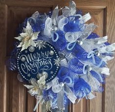 a blue and white christmas wreath hanging on a wooden door with the words merry christmas written on it