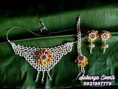 the necklace and earring are made from beads with flowers on them, sitting on a green leaf