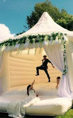 an inflatable wedding tent with two people jumping on the bed and another person laying down