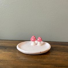 two small pink mushrooms sitting on top of a white plate with polka dot dots in the middle