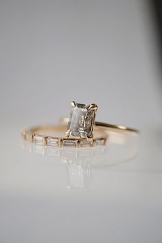 an engagement ring with a princess cut diamond in the center and baguettes on each side