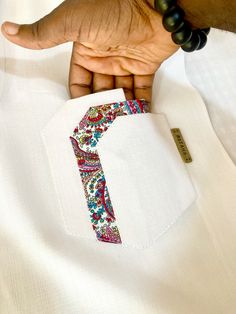 a person wearing a white shirt with a colorful design on the front and back pocket