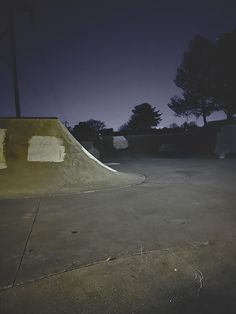 a person riding a skateboard on a ramp in the dark with trees behind them