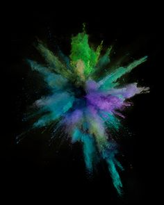 colored powder is flying in the air on a black background