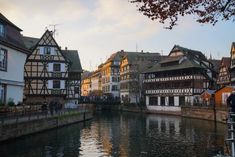 a river running through a city next to tall buildings with half timber framed windows on each side