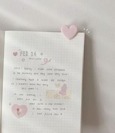 a pink teddy bear sitting on top of a piece of paper next to a note