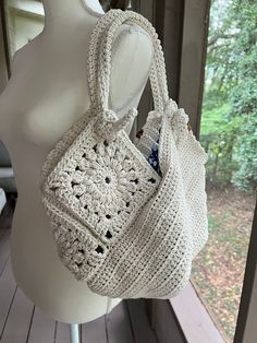 a white crocheted purse sitting on top of a mannequin