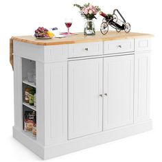 a white kitchen island with wine glasses and flowers on the counter top next to it