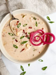 a white bowl filled with soup and topped with red onions