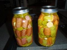 two jars filled with pickles and carrots sitting on a counter top next to each other