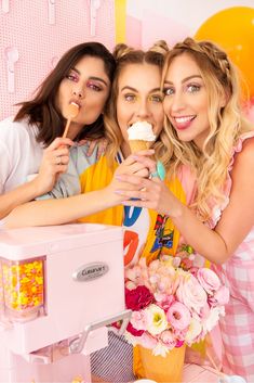 three young women eating ice cream at a pink and yellow birthday party with balloons in the background