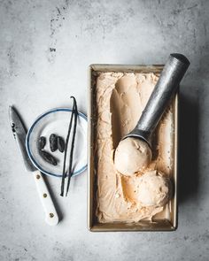 an ice cream sundae with two scoops in it and some utensils next to it