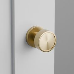 a close up of a door handle on a white and grey door with gold accents