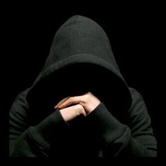 a person wearing a black hooded jacket and holding their hands over their face