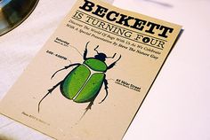 a green beetle sitting on top of a table next to a metal bowl and spoon