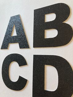 the letters are made up of black and silver glittered paper that spell out abc, c, d