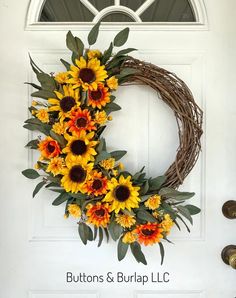 a wreath with sunflowers and greenery on the front door to a home