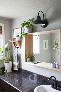 a bathroom with plants on the wall and a mirror over the sink, along with other accessories