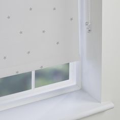 a white window with stars drawn on the roller shades in front of it and outside