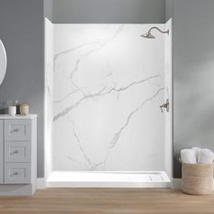 a bathroom with a white marble shower and wooden flooring next to a gray wall