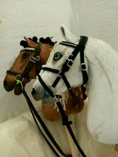 two horses wearing bridles on their heads in a room with white walls and flooring