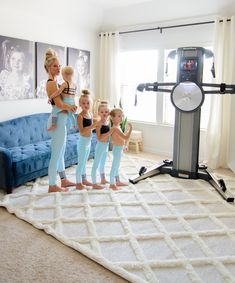 a group of women standing next to each other in front of a tv screen and exercise equipment