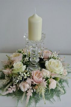 an arrangement of flowers and a candle on a table