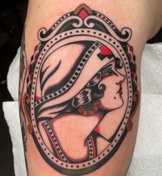 a woman's face in a mirror tattoo on the leg, with an ornate frame around it