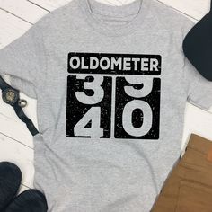 an oldometerer shirt sitting on top of a table next to some shoes and a hat