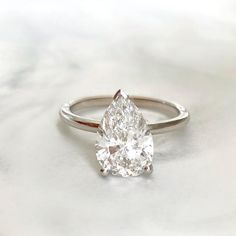 a pear shaped diamond ring sitting on top of a table