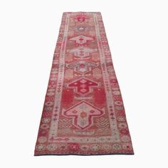 an antique persian runner rug with red and pink colors, on a white background in the shape of a rectangle