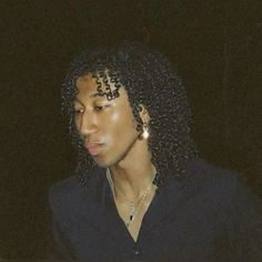 a woman with curly hair and earrings looking at her cell phone while wearing a black shirt