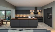 a modern kitchen with an island counter top and dark gray cabinets, along with wooden dining tables