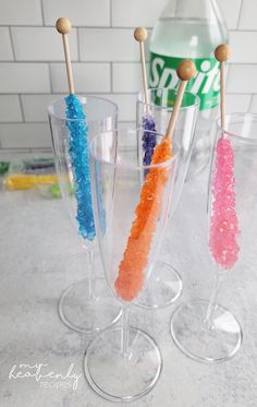 three wine glasses filled with different colored sugar sprinkles and toothbrushes