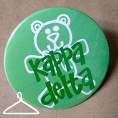 a green button with the words happy delta on it and a teddy bear sticker