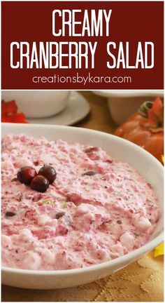 creamy cranberry salad in a white bowl with cherries on top and the text overlay reads, creamy cranberry salad