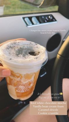 a person holding up a cup of iced coffee in their hand and driving a car