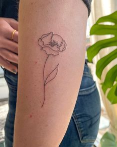 a woman's arm with a single flower tattoo on the left side of her body