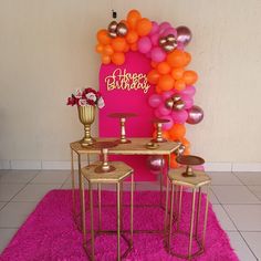 a birthday party with balloons, candles and decorations on a pink rug in front of a wall