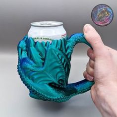 a hand is holding a green dragon mug