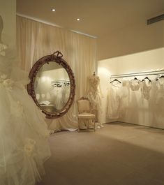 wedding gowns and dresses are on display in a bridal room with a round mirror