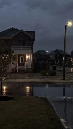 an empty street at night with lights on and water puddles in the foreground